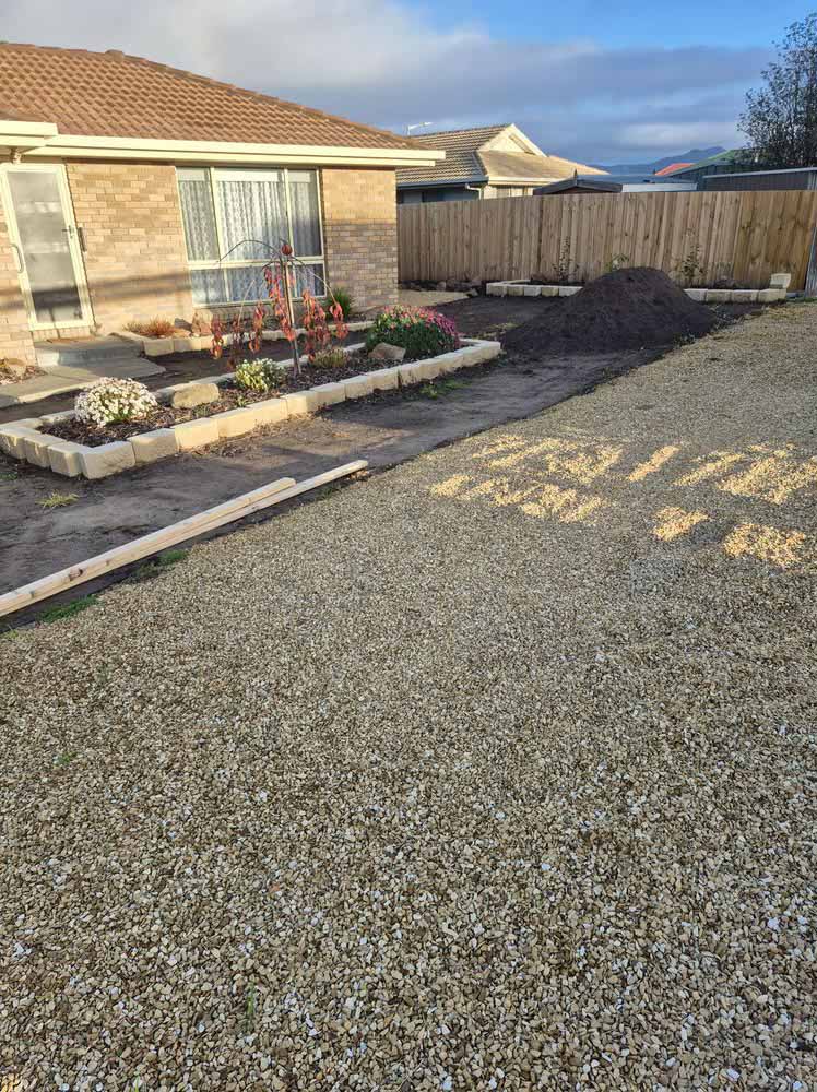Gravel yard and garden beds in front of a brick house