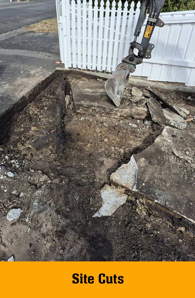 Excavator breaking up old concrete by a picket fence, labelled Site Cuts