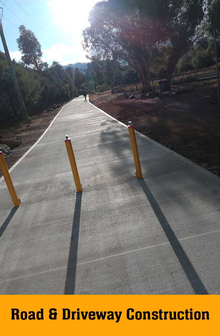 New concrete path with yellow bollards through bushland, labelled Road & Driveway Construction