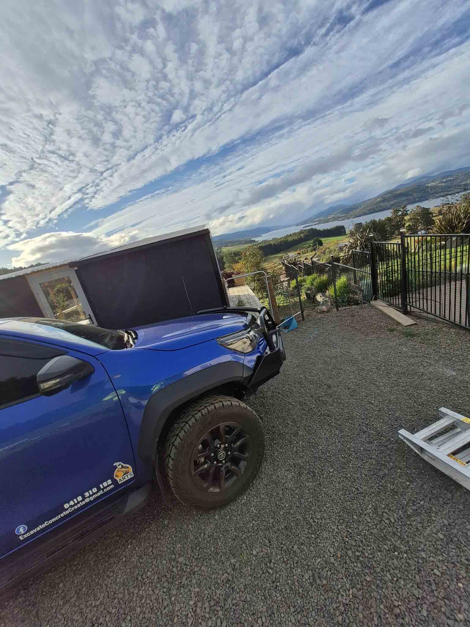 Blue ute with the ANTS logo parked on gravel overlooking a river
