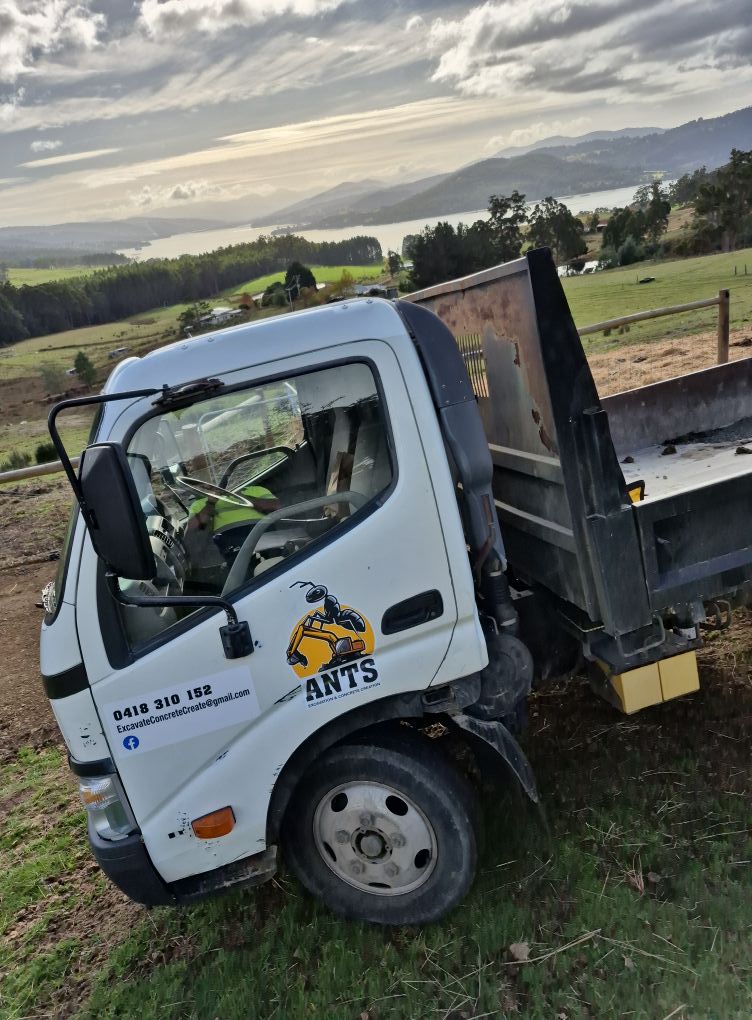 White tray truck with the ANTS logo parked on a grassy hillside