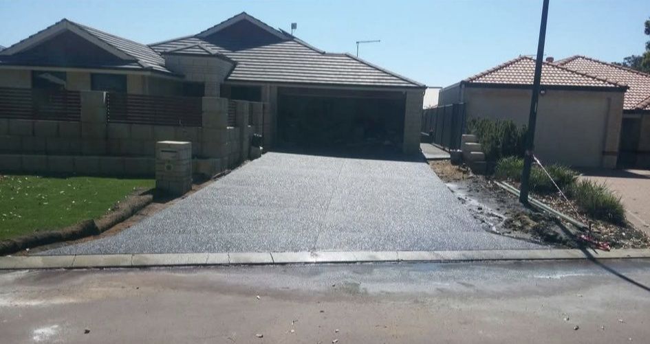 Exposed aggregate concrete driveway in front of a brick house