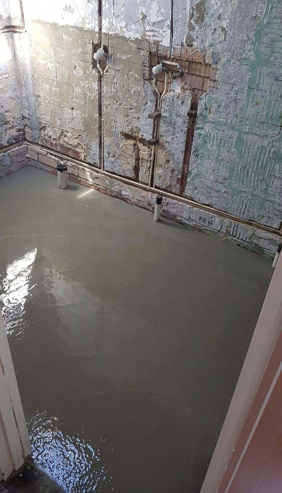 Freshly poured concrete floor in a stripped-out bathroom