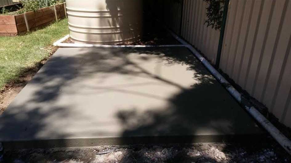 New concrete slab beside a water tank and steel fence