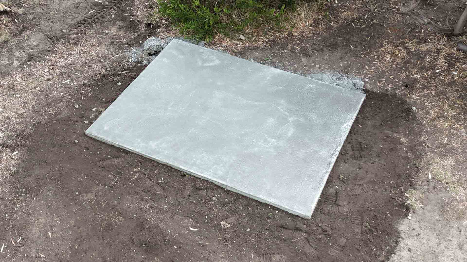 Small square concrete slab on bare soil