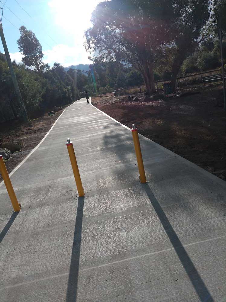 New concrete path with yellow bollards through bushland