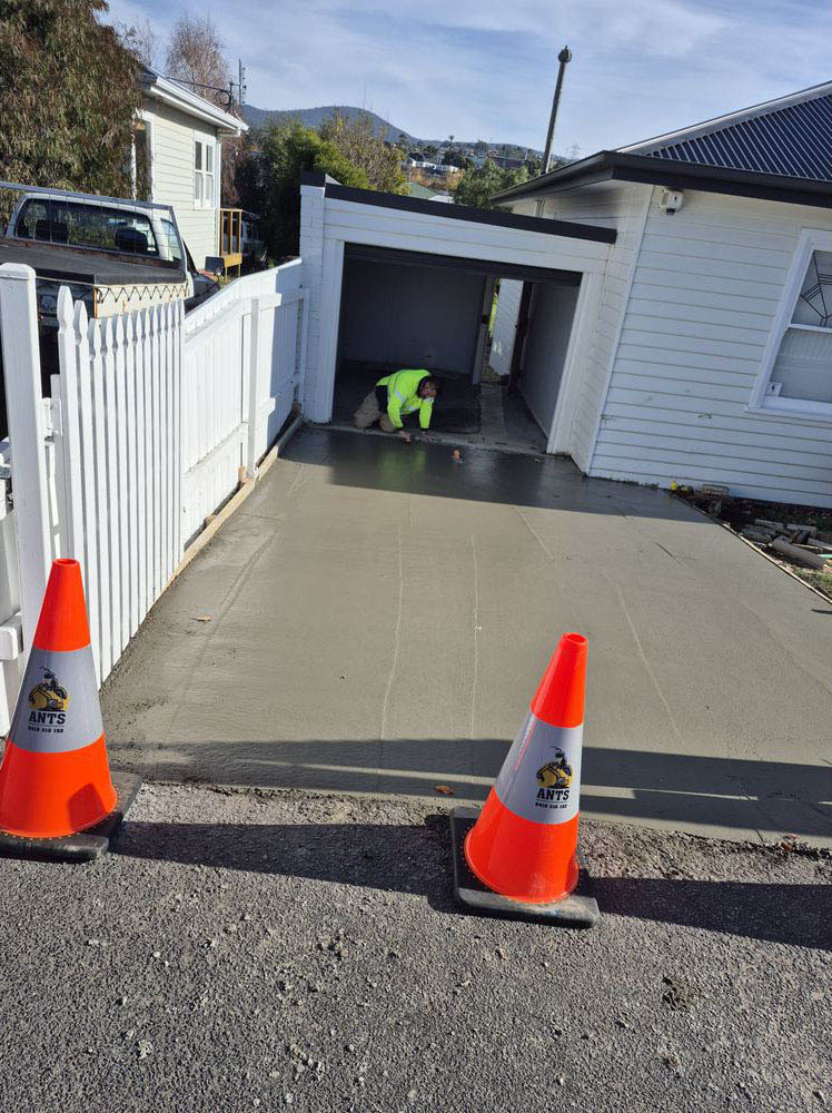 Freshly poured concrete driveway to a garage, with traffic cones