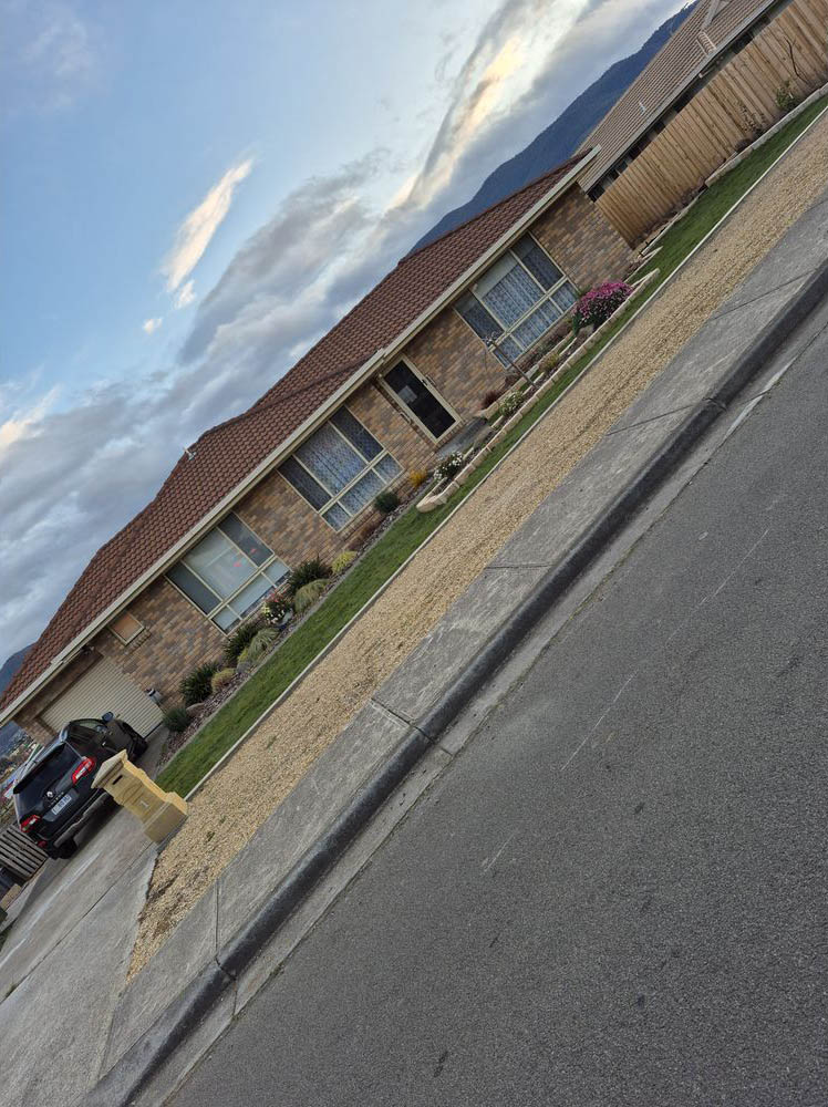 Freshly spread gravel strip along a street kerb beside brick houses