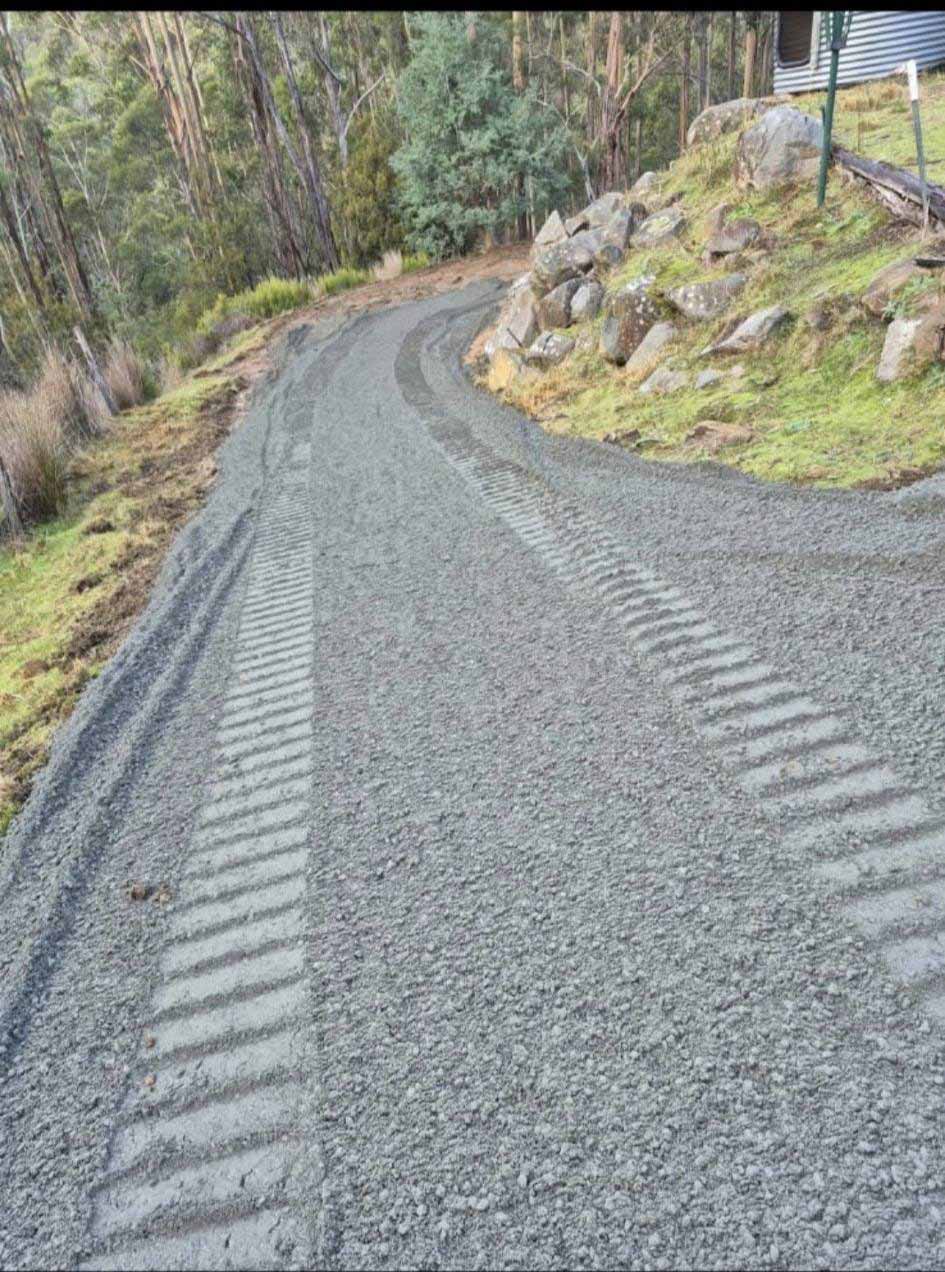 Gravel driveway winding up a bush hillside with rock edging
