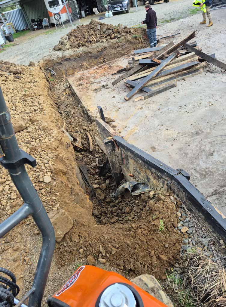 Trench dug along a concrete slab edge, seen from an excavator