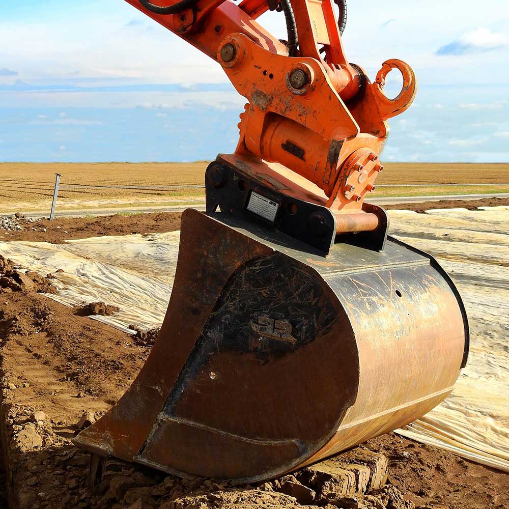 Close-up of an excavator bucket on a cleared site