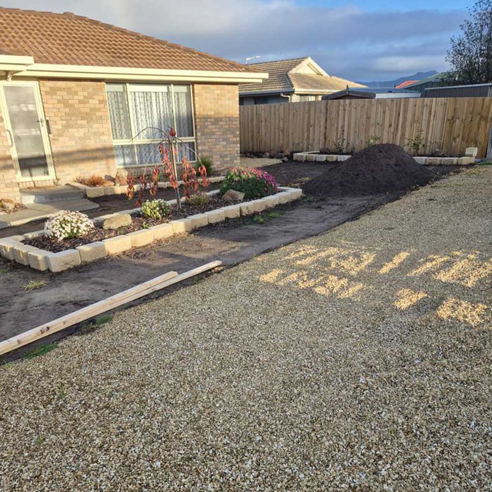 Gravel yard and garden beds in front of a brick house