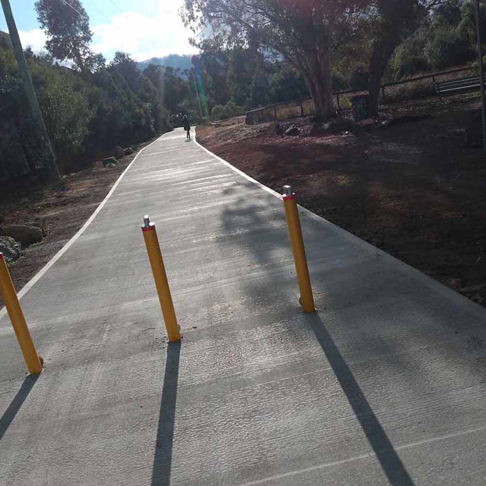 New concrete path with yellow bollards through bushland